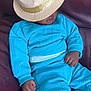 baby, child, hat, turquoise_clothing, sitting, couch, leather, hand, face_partial, indoor, relaxing, cute, young_child, blue_outfit, fashion, headwear, portrait, furniture, skin, infant