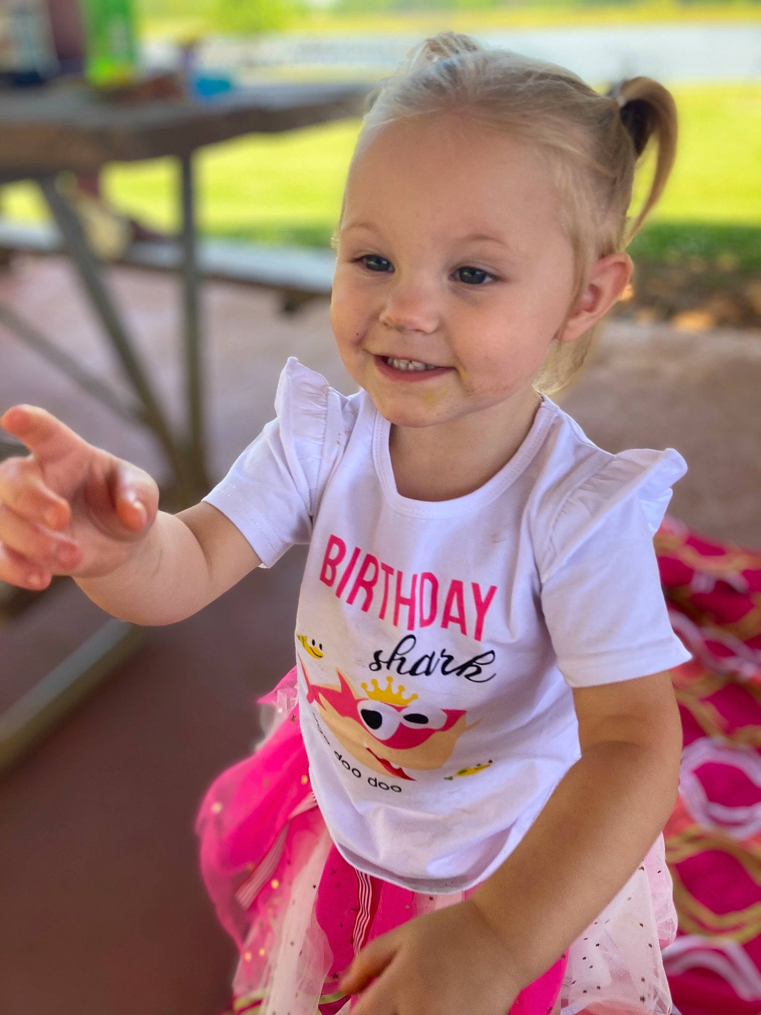 Paisley-grace is registered to the contest to win money with this photo: baby, baby_toddler_clothing, child, face, facial_expression, fun, gesture, grass, happy, joy, leisure, person, pink, recreation, skin, sleeve, smile, summer, t_shirt, table