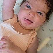 Robyn is registered to the contest to win money with this photo: animal_print, arm, baby, blanket, blue_eyes, child, closeup, clothing, cute, face, hair, hand, happy, indoors, infant, lying_down, peach_outfit, portrait, skin, smiling