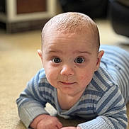 Xander is registered to the contest to win money with this photo: baby, infant, child, face, eyes, hands, carpet, blue_clothing, striped, crawling, indoor, portrait, cute, young, person, skin, head, expression, home, furniture