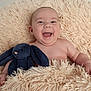 baby, smiling, laughing, stuffed_animal, plush_toy, bunny, blanket, soft_texture, child, infant, cute, happy, portrait, indoors, cozy, skin, hand, head, face, lying_down