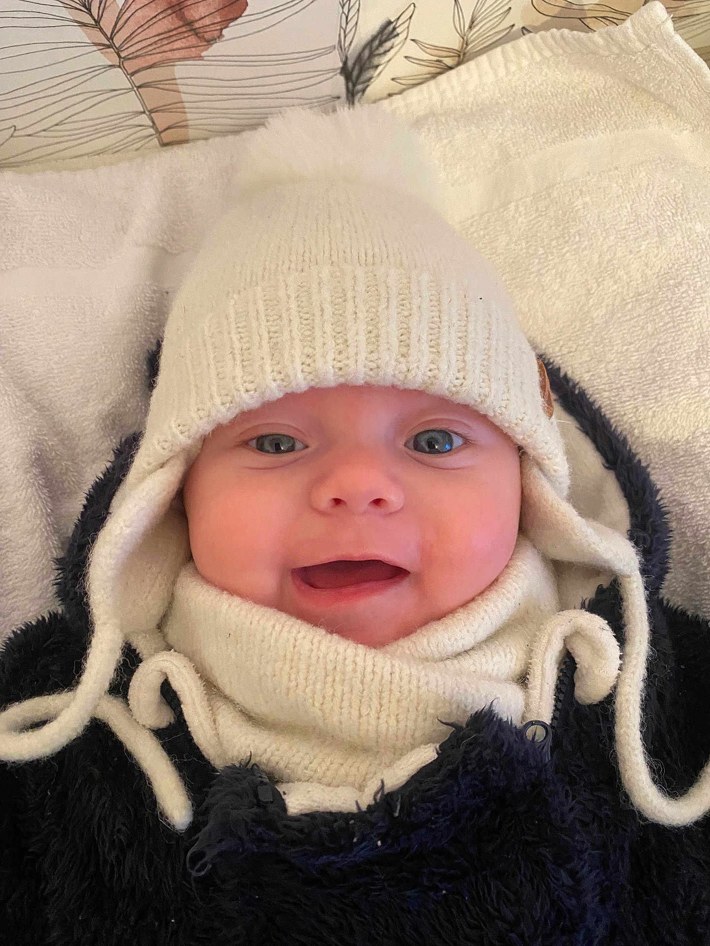 Ava participe au concours pour gagner de l'argent avec cette photo : baby, child, smile, hat, knit_hat, scarf, winter_clothing, cozy, face, blue_eyes, towel, blanket, indoor, closeup, portrait, cute, happy, warm, infant, headwear