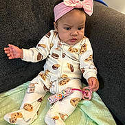 Jana is registered to the contest to win money with this photo: baby, child, indoor, pajamas, headband, pink, pacifier, blanket, couch, seated, patterned_clothing, cookie_pattern, expression, infant, soft_toys, clothing, person, cute, curious, home