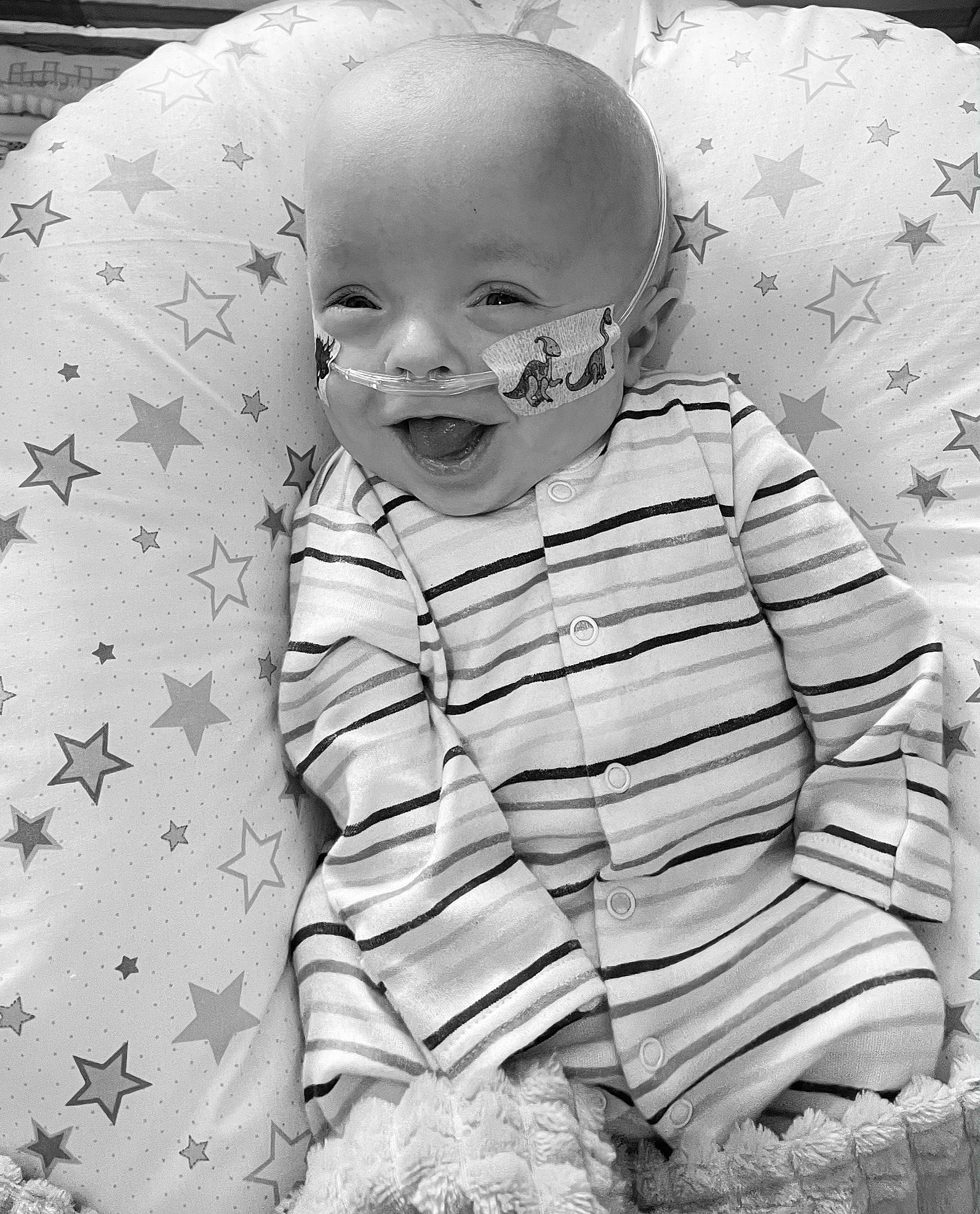 Chester is registered to the contest to win money with this photo: baby, baby_toddler_clothing, black_and_white, child, comfort, eye, grass, happy, head, iris, mammal, monochrome, monochrome_photography, pattern, person, photograph, sleeve, smile, style, toddler