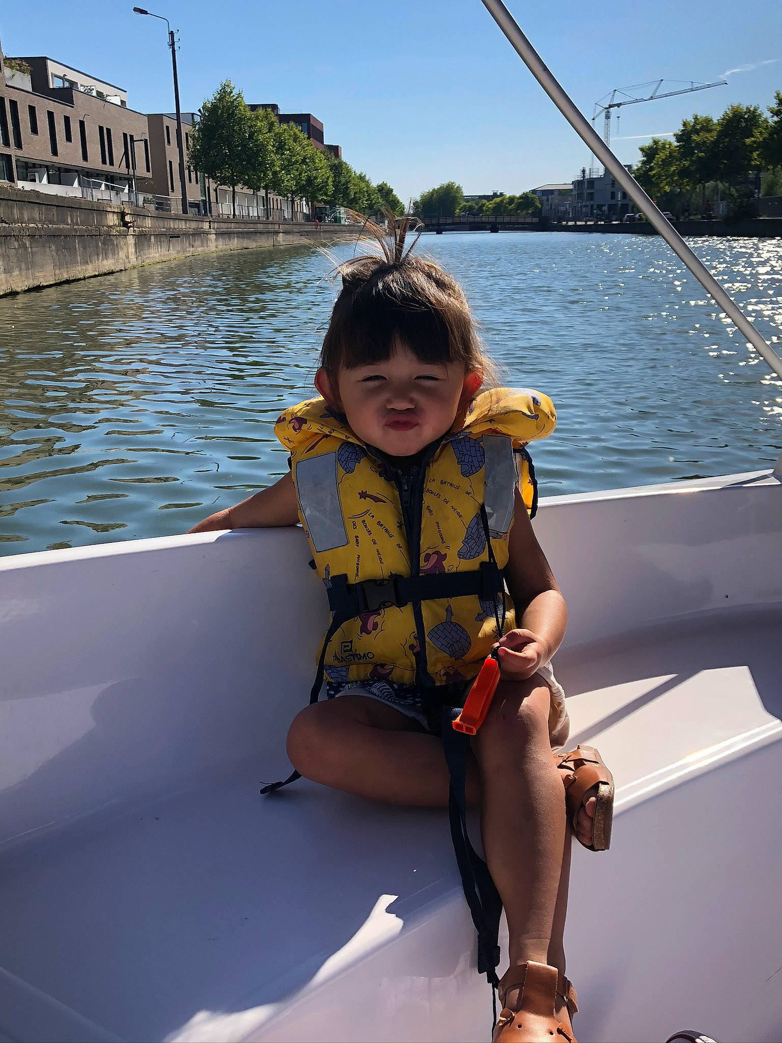 Ema participe au concours pour gagner de l'argent avec cette photo : boat, boats_and_boating_equipment_and_supplies, eye, fun, knee, lake, leisure, lifejacket, outdoor_recreation, person, recreation, sky, smile, sports_equipment, thigh, toddler, tree, vehicle, vertebrate, water