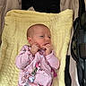 baby, infant, child, stroller, blanket, pink_clothing, yellow_blanket, sitting, lying_down, hands, fingers, face, portrait, indoors, cozy, harness, seatbelt, stroller_padding, calm, photography