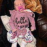 newborn, baby, sleeping, pacifier, pink_outfit, floral_clothing, blanket, couch, leather, indoors, portrait, infant, peaceful, headband, clothing, socks, seated, relaxed, closeup, family_photo