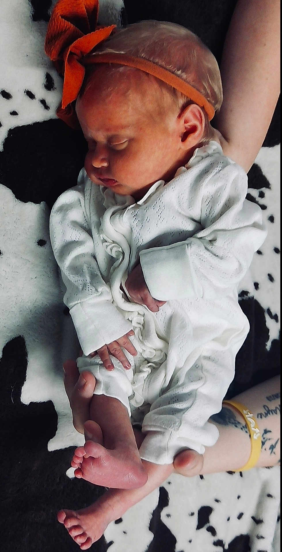 Ellie joined the competition — help win amazing prizes! baby, newborn, sleeping, onesie, headband, orange_bow, infant, tattoo, arm, hand, foot, toes, blanket, black_and_white, pattern, closeup, cute, peaceful, person, portrait