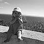 baby, barefoot, child, clouds, coast, dress, hat, monochrome, nature, outdoor, portrait, sailing_ship, scenic, sea, sky, smile, stone_wall, sun_hat, water, young_child