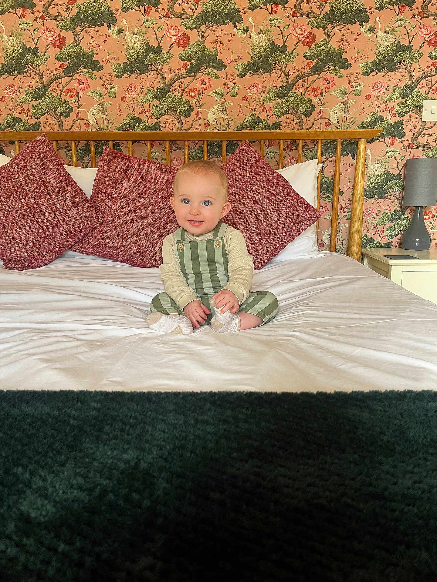 Mason joined the competition — help win amazing prizes! baby, bed, bird, blue_eyes, child, cozy, floral_pattern, headboard, interior, lamp, nightstand, pillow, room, seated, smile, socks, striped_clothing, wallpaper, white_sheet, wood