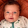 baby, infant, face, eyes, curly_hair, onesie, leaf_pattern, hedgehog_pattern, cushion, orange_background, cute, smiling, portrait, closeup, child, soft_lighting, indoors, skin, person, newborn