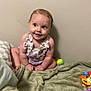 baby, infant, child, sitting, blanket, toy, colorful, wall, cute, smiling, playful, indoor, person, young, clothing, flower_pattern, skin, head, face, happy