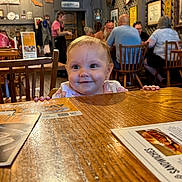 Sophia joined the competition — help win amazing prizes! baby, child, smiling, restaurant, table, wood, people, indoor, furniture, menu, happy, face, casual, seated, background, decor, light, person, cute, dining