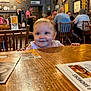 baby, child, smiling, restaurant, table, wood, people, indoor, furniture, menu, happy, face, casual, seated, background, decor, light, person, cute, dining