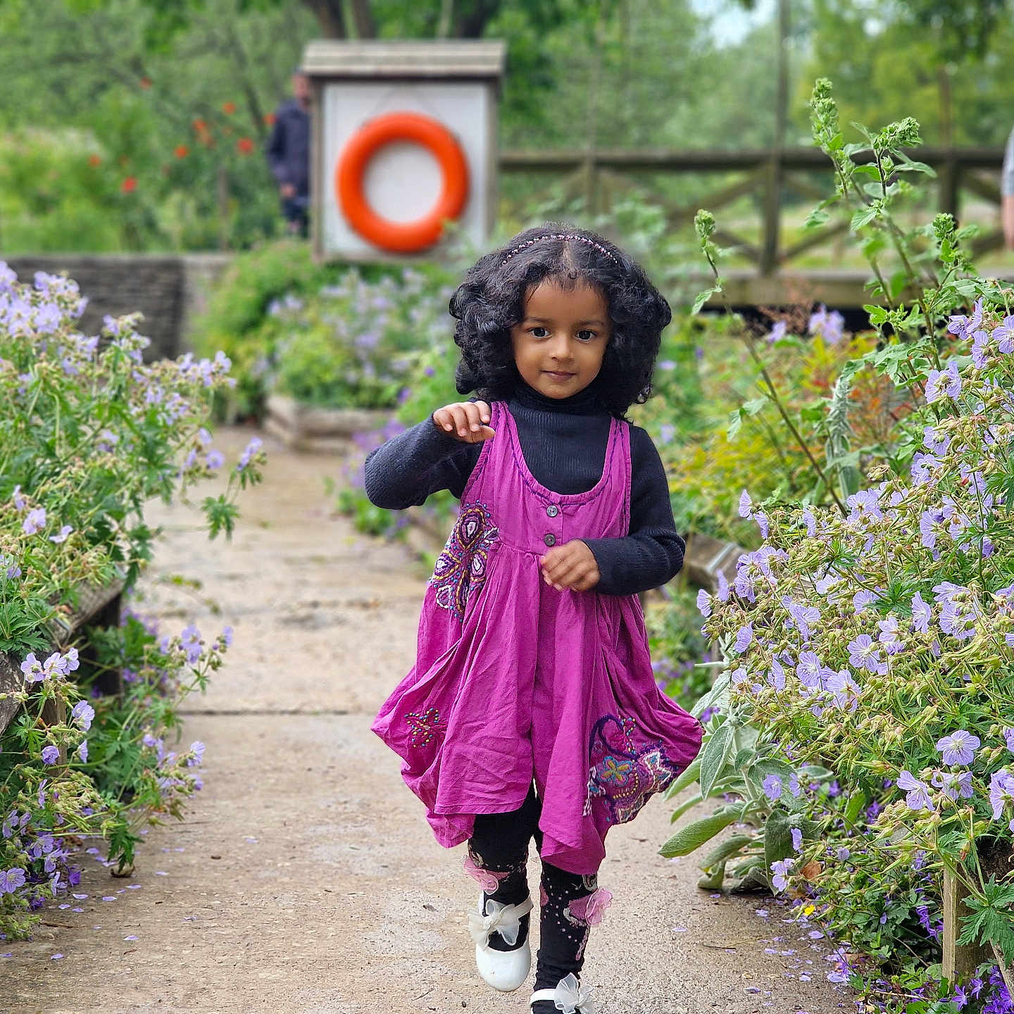 Leah joined the competition — help win amazing prizes! casual_clothing, child, curly_hair, cute, daylight, flowers, garden, girl, greenery, happy, nature, outdoor, pathway, person, plants, purple_dress, scenic, smile, spring, walking