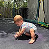 Joshua joined the competition — help win amazing prizes! baby, barefoot, child, crouching, curious, daylight, fence, gray_shorts, nature, netting, outdoor, play, shadow, striped_shirt, summer, sunlight, toddler, trampoline, trees, young_child
