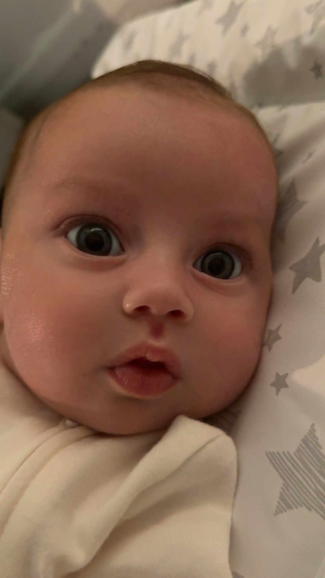 Erin joined the competition — help win amazing prizes! baby, infant, face, wide_eyes, curious, close_up, blanket, star_pattern, soft_lighting, skin, cheeks, mouth, clothing, sleepwear, newborn, portrait, indoors, cute, expression, child
