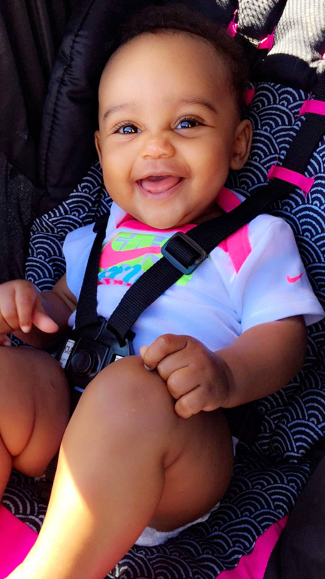 London is registered to the contest to win money with this photo: baby, baby_products, beauty, black, black_hair, cheek, child, face, finger, happy, joy, leg, lip, person, pink, sitting, skin, smile, thigh, toddler