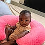 Joie is registered to the contest to win money with this photo: baby, infant, child, pink_pillow, bed, striped_onesie, curly_hair, earrings, skin, small_hands, small_feet, comfort, indoor, cushion, soft_texture, looking_at_camera, cute, adorable, relaxing, young