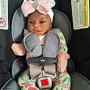 Joie is registered to the contest to win money with this photo: baby, car_seat, child, infant, headband, pink_bow, floral_onesie, straps, safety_harness, cute, small_hands, mittens, face, looking, indoors, seat, child_safety, adorable, portrait, young_child