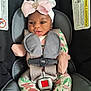 baby, car_seat, child, infant, headband, pink_bow, floral_onesie, straps, safety_harness, cute, small_hands, mittens, face, looking, indoors, seat, child_safety, adorable, portrait, young_child
