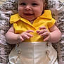 baby, baby_girl, child, clothing, cute, eyes, face, flower_decorations, hand, happy, head, indoor, infant, pillow, portrait, skin, smiling, white_pants, yellow_bows, yellow_top