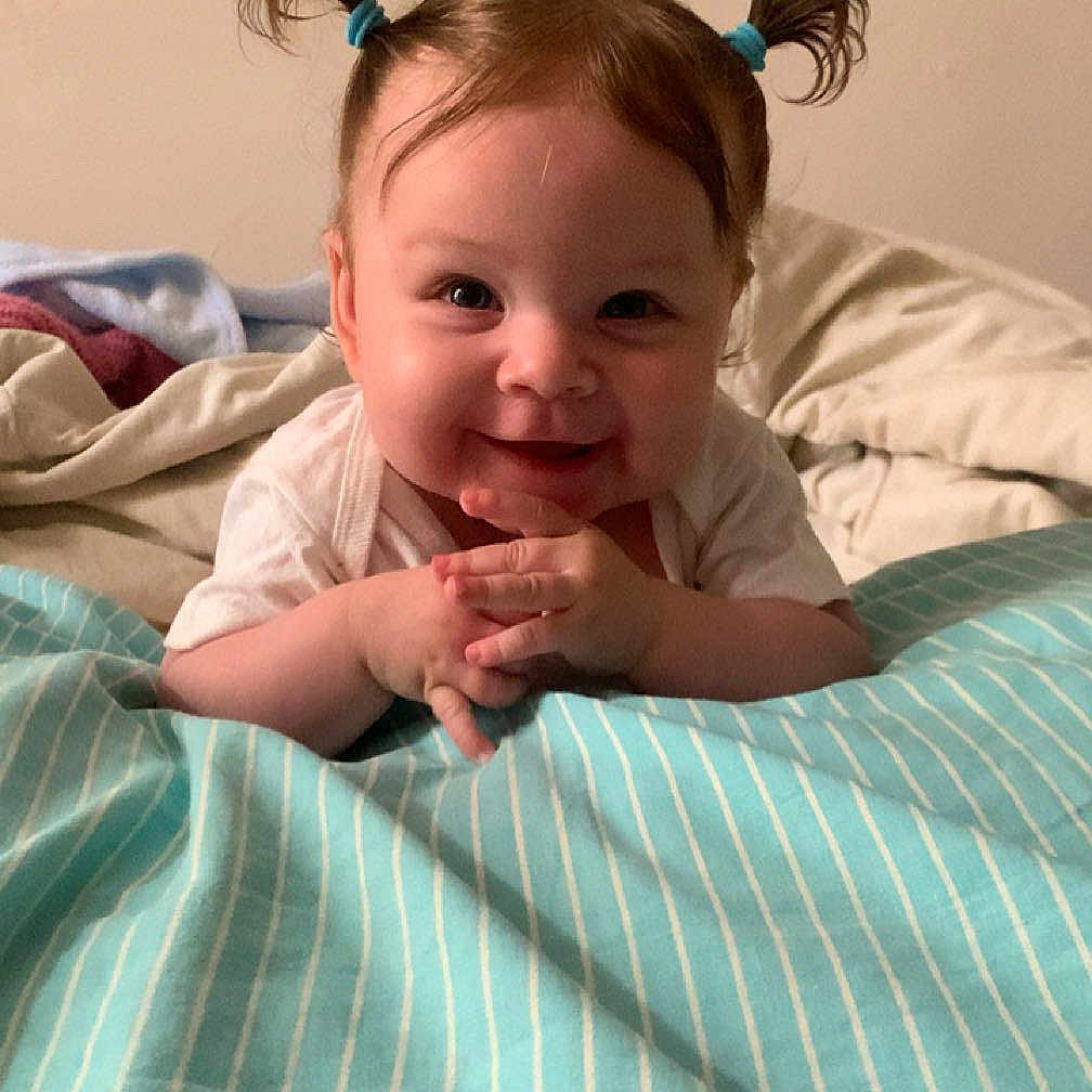 Siana Castagna participe au concours pour gagner de l'argent avec cette photo : baby, bed, blanket, child, clothing, cute, face, hair, hands, happy, indoors, infant, lying_down, person, pigtails, skin, small_hands, smile, striped_blanket, young_child