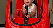 Wyatt is registered to the contest to win money with this photo: baby, child, toy_car, red, rescue, indoor, play, expression, joy, handle, seat, vehicle, amusement, fun, person, cute, small, happy, entertainment, mall