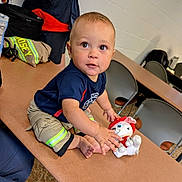 Wyatt is registered to the contest to win money with this photo: toddler, child, toy, plush, firefighter_clothing, shorts, shirt, table, chair, indoor, curious, person, cute, baby, caucasian, floor, carpet, backpack, stuffed_animal, play