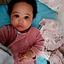 baby, infant, child, pink_clothing, blanket, unicorn_pattern, rainbow_pattern, bed, soft_toys, cute, lying_down, indoors, portrait, face, hand, curly_hair, expression, comfort, cozy, sleepwear