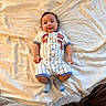 baby, infant, bed, blanket, clothing, onesie, socks, smile, face, person, sleepwear, cute, indoor, lying_down, young_child, bedroom, soft, comfort, happy, portrait