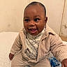Mamady participe au concours pour gagner de l'argent avec cette photo : baby, child, smiling, happy, indoor, bed, blanket, clothing, corduroy, jacket, pants, bear_pattern, cute, person, portrait, sitting, face, head, infant, cozy