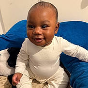 Mamady a rejoint le concours — aidez-le/la à gagner de superbes lots ! baby, infant, child, smiling, sitting, pajamas, blanket, cushion, blue, beige, indoors, cute, happy, face, person, young, cozy, comfort, portrait, skin