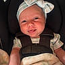 baby, infant, car_seat, headband, bow, smile, tongue, blanket, child, seatbelt, cute, young_child, person, apparel, indoor, closeup, happy, face, skin, clothing