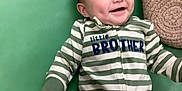 Brian is registered to the contest to win money with this photo: baby, smiling, infant, striped_clothing, onesie, green_mat, pillow, toy, happy, dimples, lying_down, child, cute, indoor, playtime, young_child, person, face, apparel, fabric