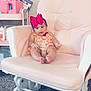 Helena joined the competition — help win amazing prizes! baby, child, pink_bow, rocking_chair, cushion, carpet, nursery, infant, clothing, person, indoor, furniture, soft_lighting, cute, portrait, sitting, happy, baby_supplies, storage_cart, floor