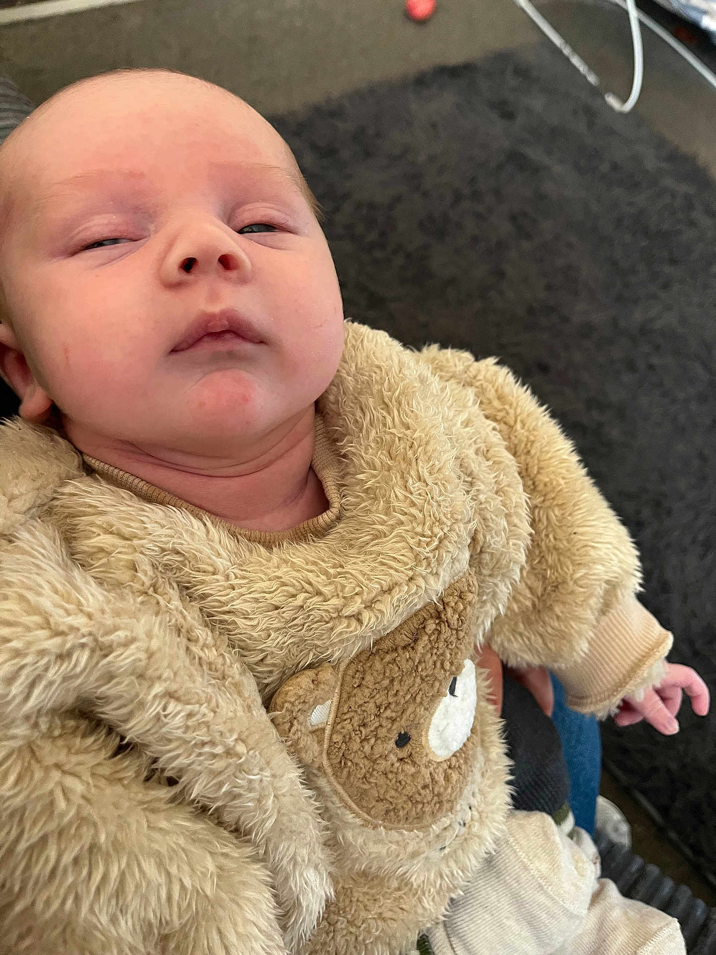 Tommy joined the competition — help win amazing prizes! baby, infant, child, fuzzy_clothing, bear_design, sleepy, indoor, carpet, hand, person, cute, soft_texture, apparel, young, toddler, cozy, portrait, closeup, human, casual