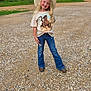 child, girl, cowboy_hat, tshirt, horses, jeans, boots, gravel, path, outdoor, trees, fence, nature, smile, blonde_hair, posing, rural, casual_clothing, sunlight, happy