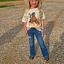 Presley is registered to the contest to win money with this photo: child, girl, cowboy_hat, tshirt, horse_print, jeans, brown_shoes, bracelet, outdoor, gravel, trees, grass, smiling, blonde_hair, long_hair, shadow, sunny, nature, standing, portrait