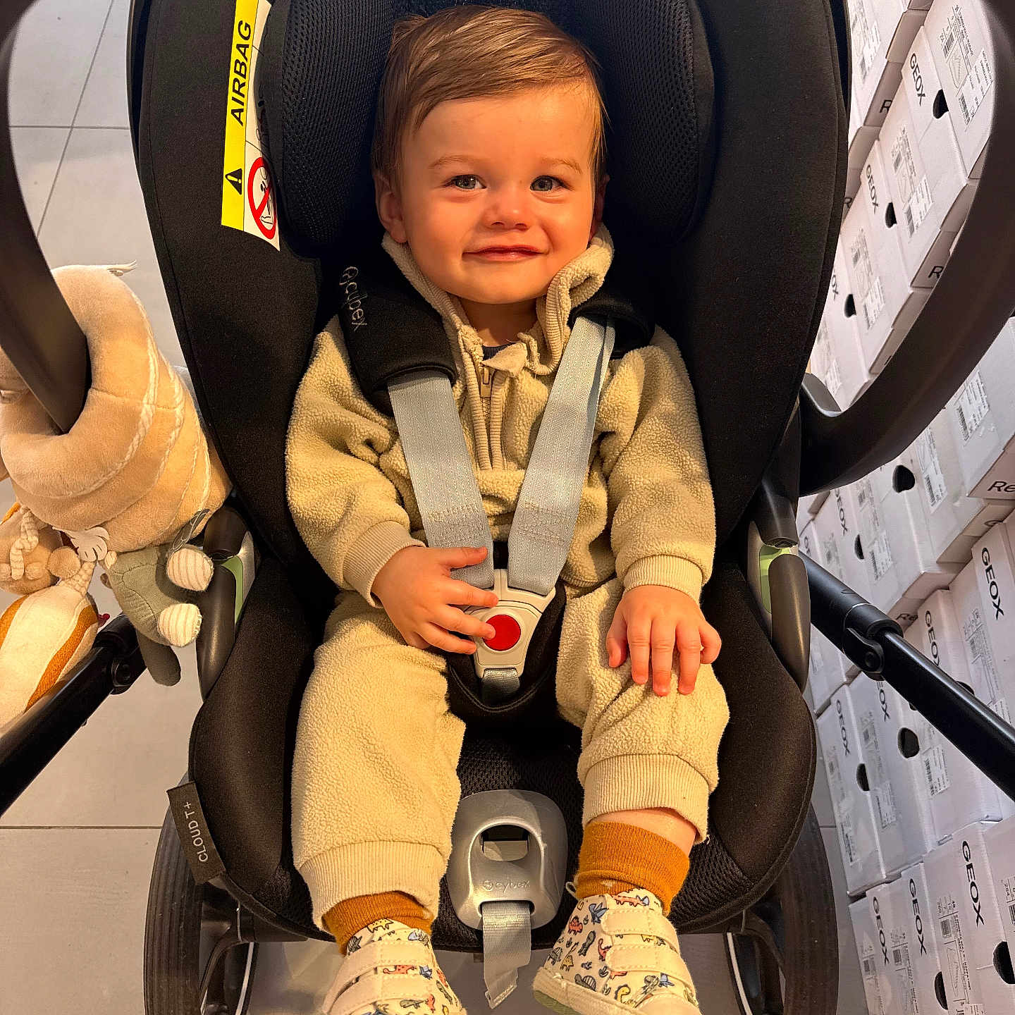 Noah participe au concours pour gagner de l'argent avec cette photo : toddler, child, car_seat, smile, fleece_clothing, shoes, socks, toy, stroller, boxes, indoor, face, person, seatbelt, happy, cute, baby, floor, head, clothing