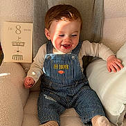 Noah participe au concours pour gagner de l'argent avec cette photo : baby, infant, child, smiling, overalls, striped_clothing, socks, armchair, pillow, cozy, indoor, milestone_card, age_card, sunlight, shadow, happy, cute, portrait, person, soft_fabric