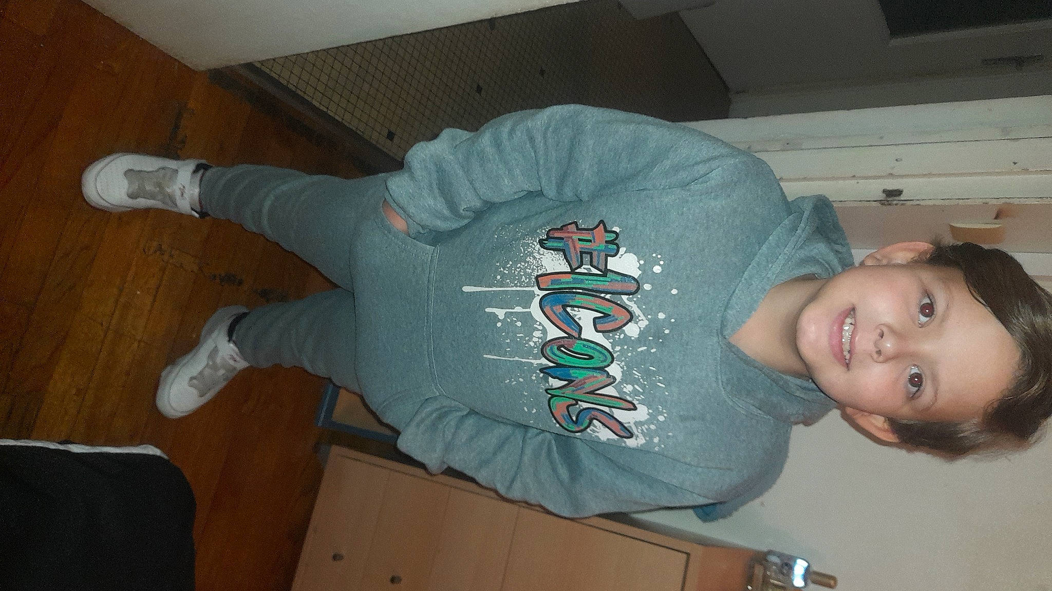 Adem participe au concours pour gagner de l'argent avec cette photo : active_shirt, baby_toddler_clothing, comfort, elbow, electric_blue, flooring, happy, hardwood, head, joy, knee, person, sleeve, smile, t_shirt, thigh, thumb, top, trunk, wood