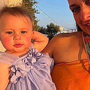 Bea is registered to the contest to win money with this photo: toddler, child, woman, outdoor, dress, lavender, orange, smile, face, portrait, string_lights, sunlight, blue_sky, trees, holding, happy, fashion, person, nature, event