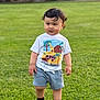 toddler, child, grass, outdoor, shorts, tshirt, curly_hair, standing, greenery, playful, daylight, nature, young_child, casual_clothing, person, cute, summer, feet, expression, park