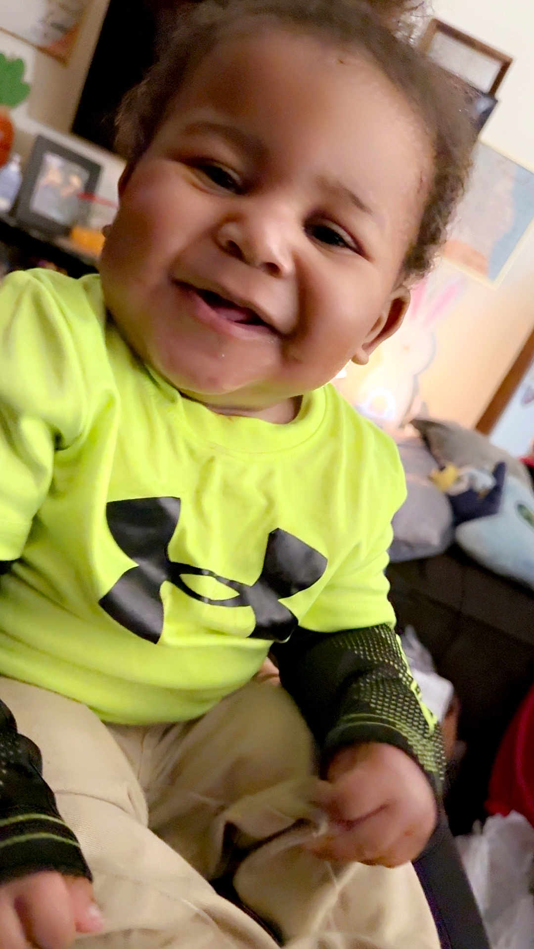 Matteo joined the competition — help win amazing prizes! toddler, child, smiling, indoor, neon_shirt, logo, happy, person, face, cushions, toy, casual_clothing, sitting, home, cute, young_child, portrait, bright_color, hand, hair