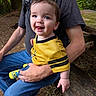 Paxxton is registered to the contest to win money with this photo: baby, child, adult, person, outdoor, bench, wood, greenery, nature, happy, smiling, yellow_clothing, jeans, socks, forest, casual, portrait, holding, daylight, family