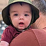 Paxxton joined the competition — help win amazing prizes! baby, child, face, hat, bucket_hat, green_hat, clothing, person, portrait, closeup, expression, curious, infant, holding, adult, shoulder, casual, indoor, skin, eyes