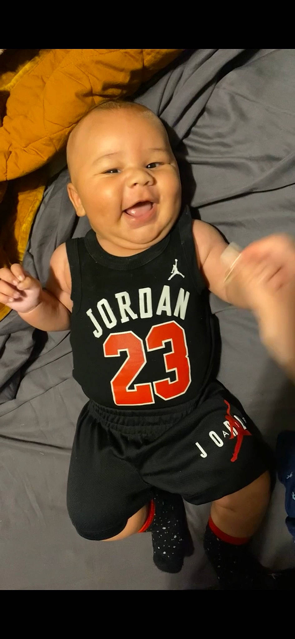 Carter is registered to the contest to win money with this photo: baby_toddler_clothing, child, chin, face, finger, gesture, happy, head, jersey, orange, person, sleeve, sleeveless_shirt, smile, sports_jersey, sports_uniform, sportswear, t_shirt, thumb, toddler