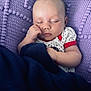 Amani is registered to the contest to win money with this photo: baby, sleeping, blanket, knitted, purple, navy_blue, infant, peaceful, cute, face, hand, cozy, resting, soft, closeup, person, indoors, clothing, toddler, portrait