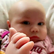 Amani is registered to the contest to win money with this photo: baby, foot, hand, close_up, indoor, person, skin, pink_clothing, infant, face, human, cute, soft_focus, child, newborn, pajamas, relaxed, lying_down, background_blur, young